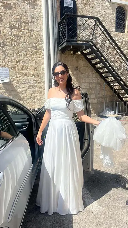 כלה בשמלה לבנה חלקה עם כתפיים חשופות, גזרה קלאסית ונשית