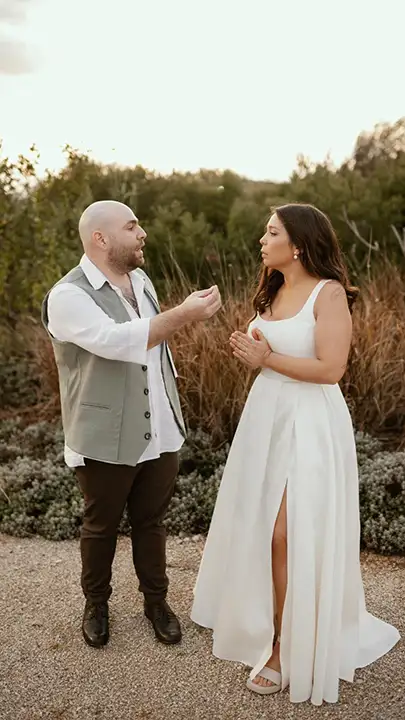 כלה בשמלה לבנה בגזרה חלקה עם כתפיות עבות, שסע קדמי ונפילה רכה